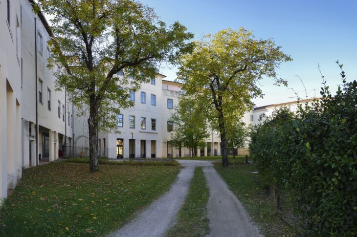 Area verde interna con alberi, percorso pedonale e affaccio sugli edifici della struttura.