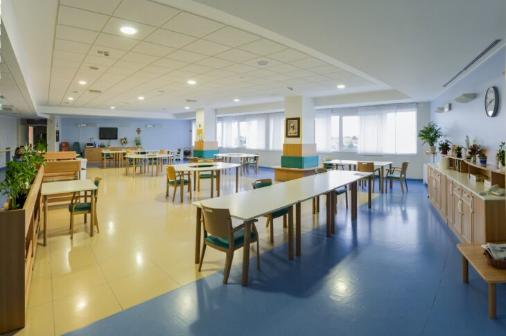 Ampia sala comune con tavoli, sedie e spazi dedicati alle attività degli ospiti.